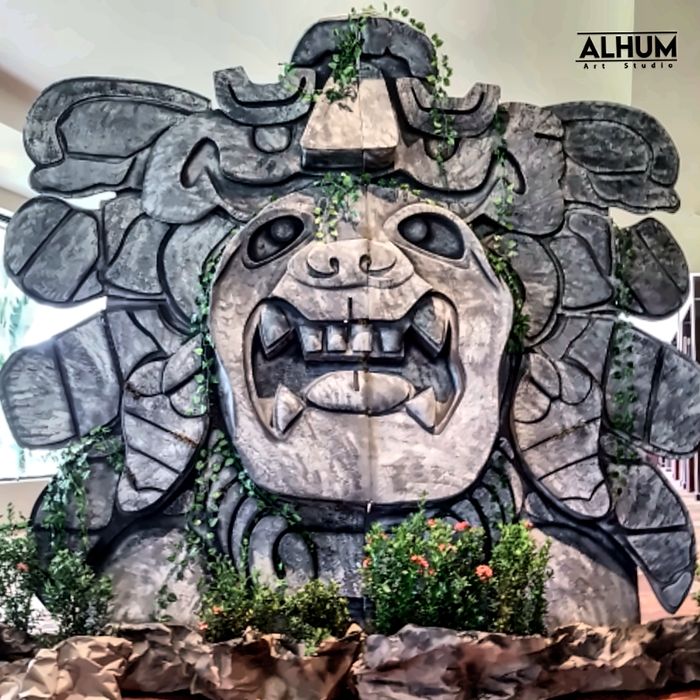 Mascarón de piedra de fauces abiertas, cubierto de enredaderas