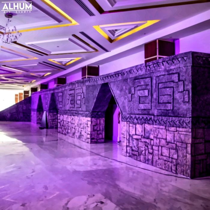 Muro con arcos y grecas mayas en un salón con luz morada