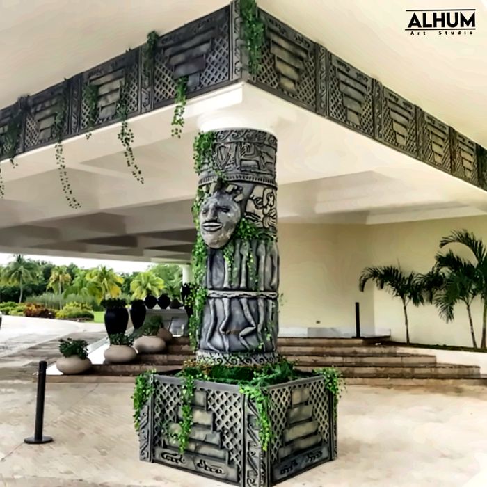 Columna tallada con rostro y enredaderas en la entrada de un hotel